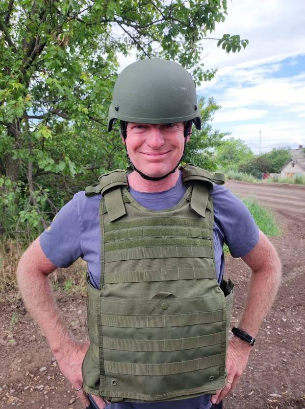 Jon Heath poses for a picture with a vest and helmet on.